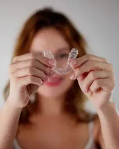 a woman holding clear aligner trays